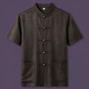 Flat lay of the men's short-sleeve silk shirt, showing the detailed geometric pattern, wooden button details, and patch pockets.