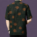 Back view of the dark green silk shirt, highlighting the large, blurred rust-colored dots that scatter across the matte fabric.