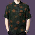 Men's dark green 100% mulberry silk short-sleeve shirt with a stand collar and rust-brown watercolor polka dot pattern, styled with black trousers.