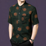 Front view of the green silk top, showcasing the relaxed straight cut and a single chest pocket on the left side.