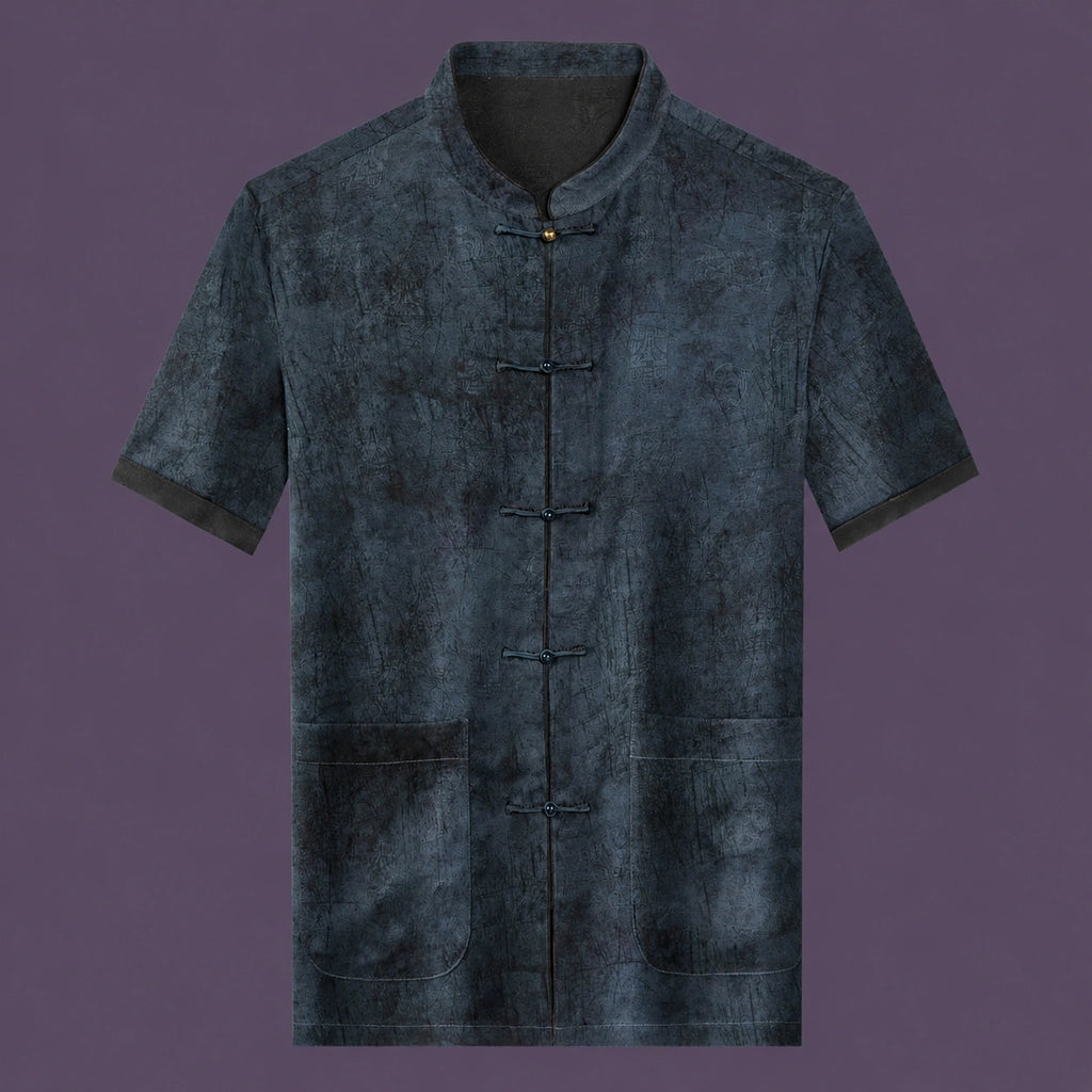 Flat lay of the men's grey silk short-sleeve top featuring a mandarin collar, six frog buttons, two patch pockets, and contrast binding on the cuffs.