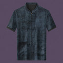 Flat lay of the men's grey silk short-sleeve top featuring a mandarin collar, six frog buttons, two patch pockets, and contrast binding on the cuffs.