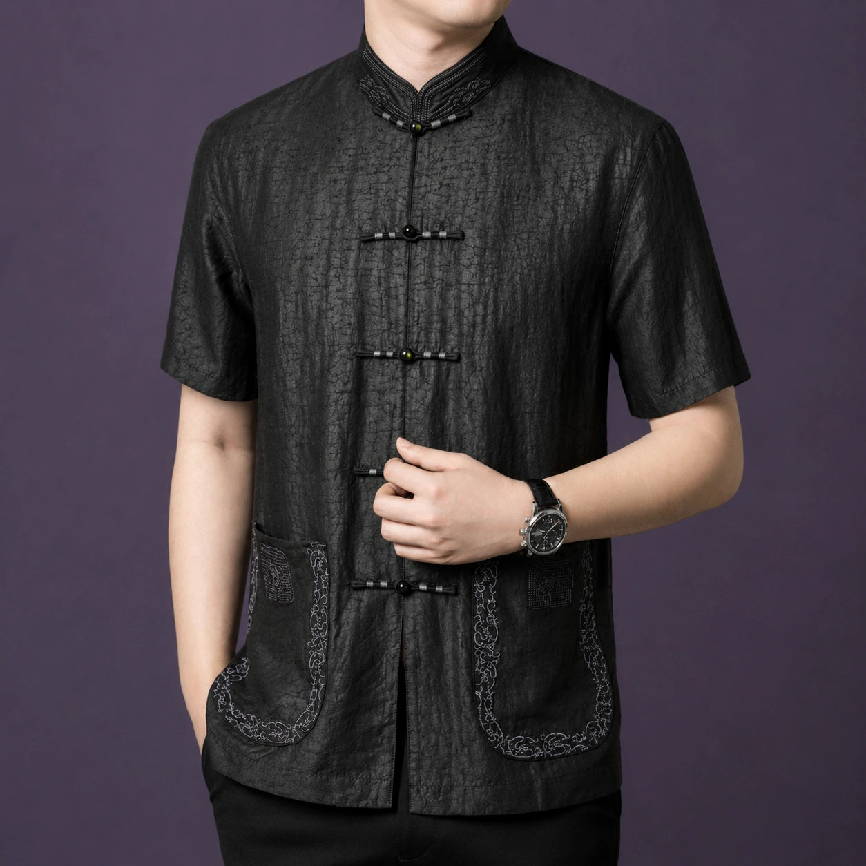 Close-up of a men's black mulberry silk Mandarin collar shirt with embroidered pockets and traditional frog button closure.