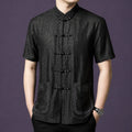 Model wearing a black embroidered mulberry silk Tang shirt with Mandarin collar and frog buttons.