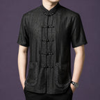 Model wearing a black embroidered mulberry silk Tang shirt with Mandarin collar and frog buttons.