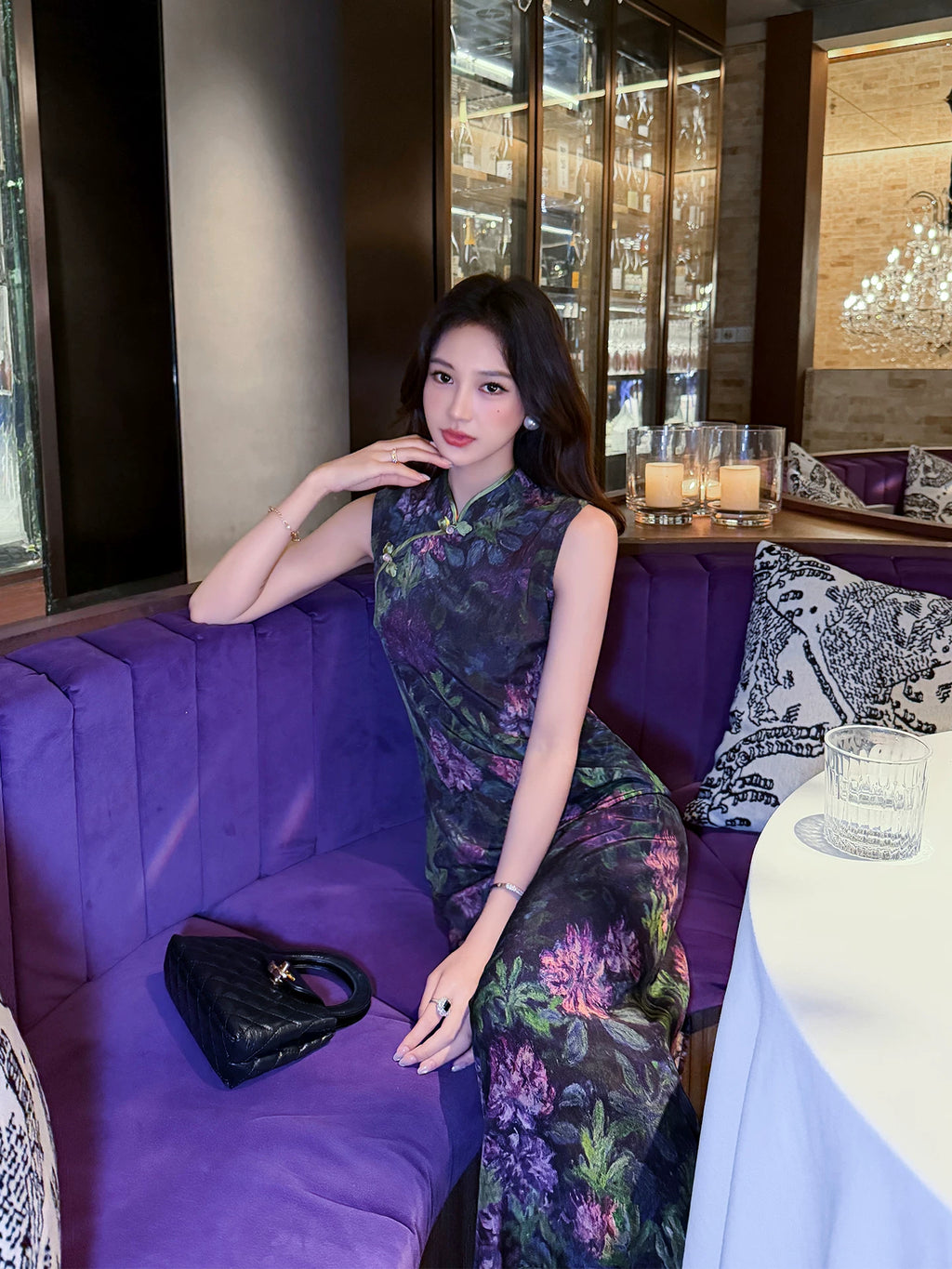 Woman wearing a Midnight Botanical Mulberry Silk floral Cheongsam dress while seated in an elegant restaurant.