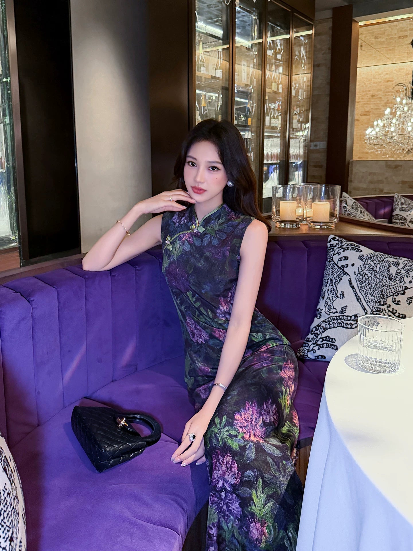 Woman wearing a Midnight Botanical Mulberry Silk floral Cheongsam dress while seated in an elegant restaurant.