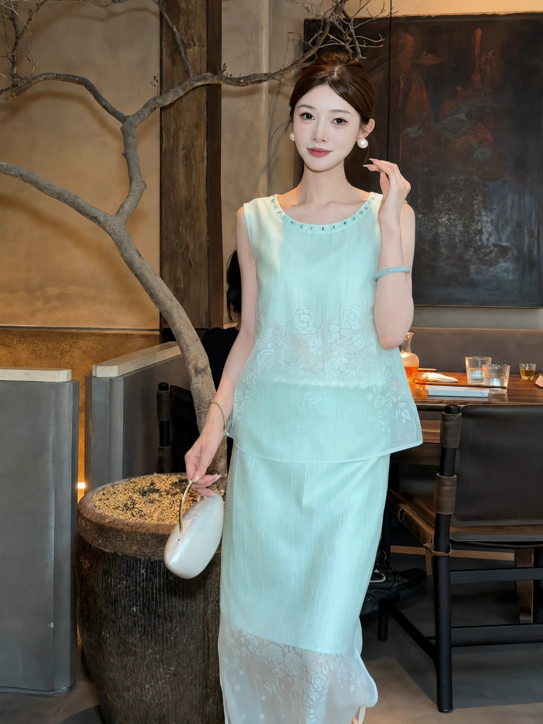Front view of a mint green Cheongsam-style set with floral embroidery, styled with a white bag, showcasing the elegant drape of the Lyocell-blend fabric.