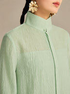 Close-up of the stand collar and hidden front placket button on a mint green lyocell-linen blend long dress, showing the natural crinkled texture.