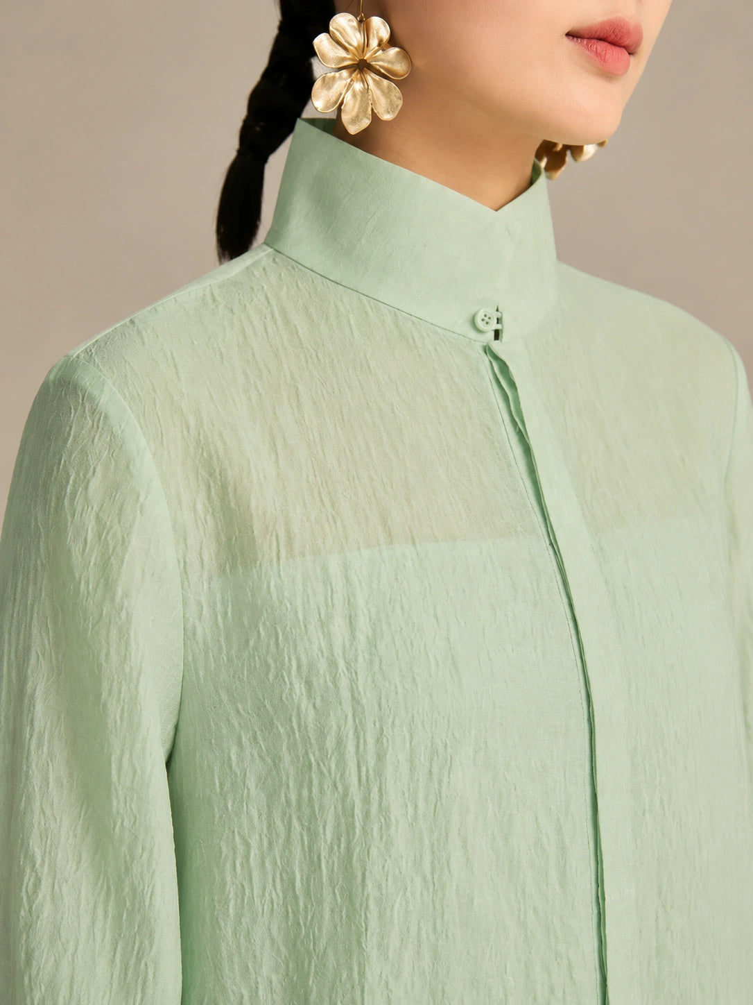 Close-up of the stand collar and hidden front placket button on a mint green lyocell-linen blend long dress, showing the natural crinkled texture.