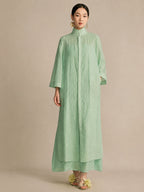 Front view of a mint green lyocell-linen stand collar dress with a concealed button closure, styled with gold floral earrings.