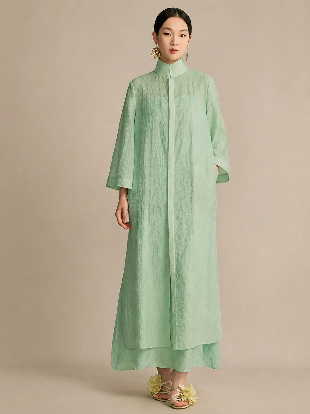 Front view of a mint green lyocell-linen stand collar dress with a concealed button closure, styled with gold floral earrings.