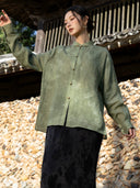 Close view of a mist green shirt showing its textured fabric, stand collar, decorative neckline loop and small contrasting front buttons.