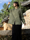 Front view of a mist green shirt with dropped shoulders, a stand collar and contrasting buttons, shown with one arm raised.
