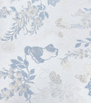 Macro view of a blue cat motif woven among floral details on the vest.