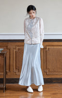 Front view of the sleeveless jacquard vest, showing its curved front panel and blue buttons.