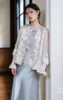 Portrait view of the mist silver vest layered over a sheer-sleeve white top.