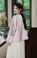 Model turning to show the back of the misty lavender jacket and its embroidered ivory cuff.
