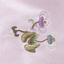 Close-up of multicoloured floral embroidery on misty lavender fabric.