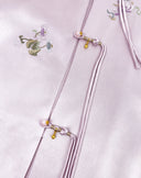 Close-up of floral embroidery and decorative knot closures with gold accents on the jacket.