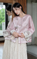 Model beside a mirror wearing the misty lavender jacket with embroidered cuffs and an ivory skirt.