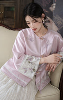 Seated model wearing the misty lavender jacket, showing its floral details and contrast cuffs.