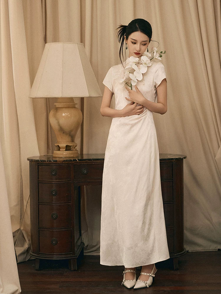 Ivory jacquard qipao dress with floral texture styled for an elegant indoor setting.