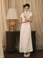 Ivory jacquard qipao dress with floral texture styled for an elegant indoor setting.