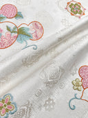Close-up of the vest’s tonal white fabric pattern and colourful gourd embroidery.