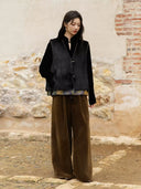 Full-length outfit featuring the black fur side of the Moxu vest with a black blouse and brown wide-leg trousers.