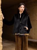 Model wearing the black fur side of the Moxu vest with one hand in a side pocket beside a textured wall.