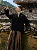 Model wearing the coat with one arm raised, showing its asymmetrical front.
