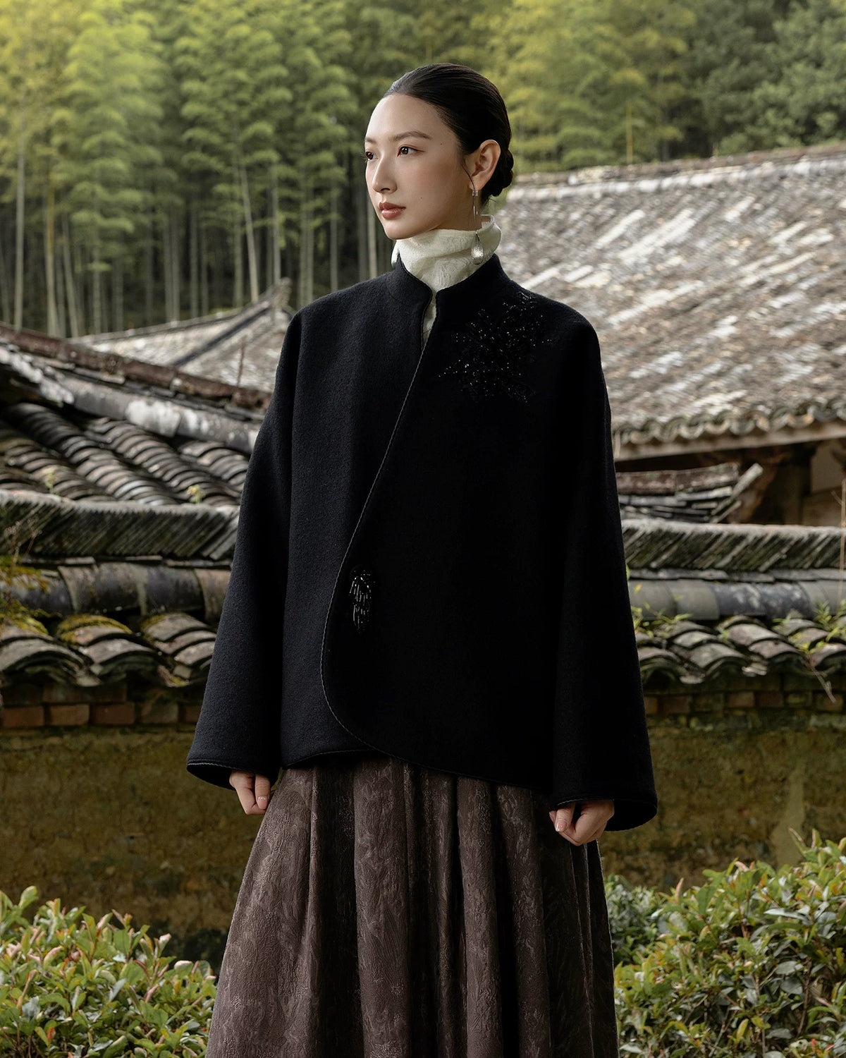 Model wearing the Jinyu Black wool coat with a brown skirt outdoors.
