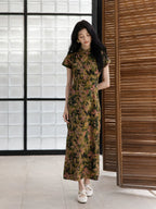 Woman wearing a botanical print mulberry silk Chinese dress in a relaxed indoor setting.