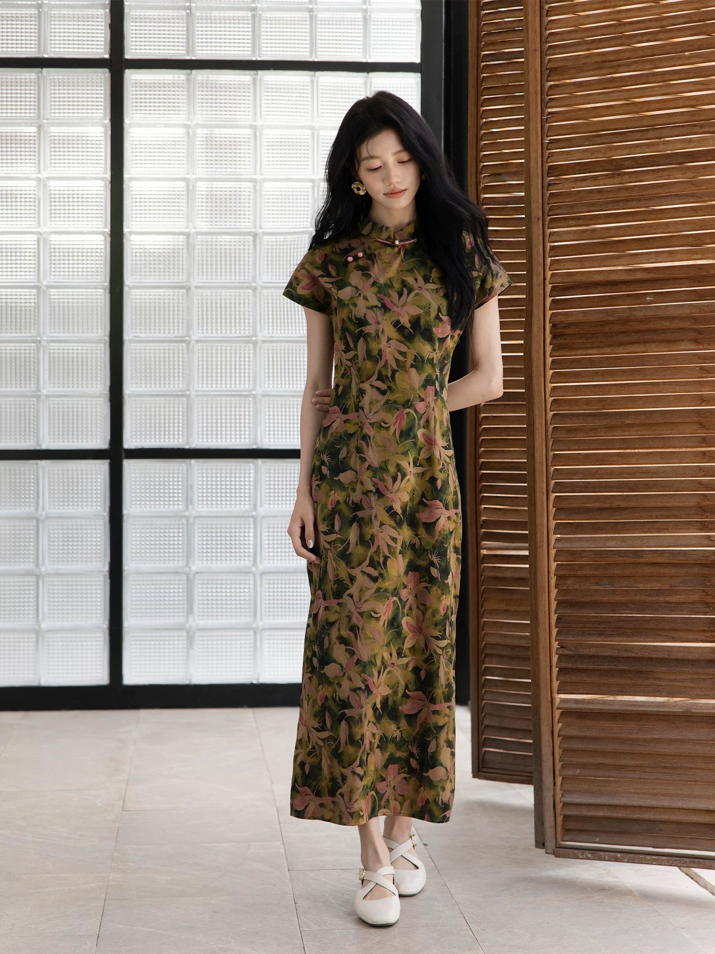 Woman wearing a botanical print mulberry silk Chinese dress in a relaxed indoor setting.