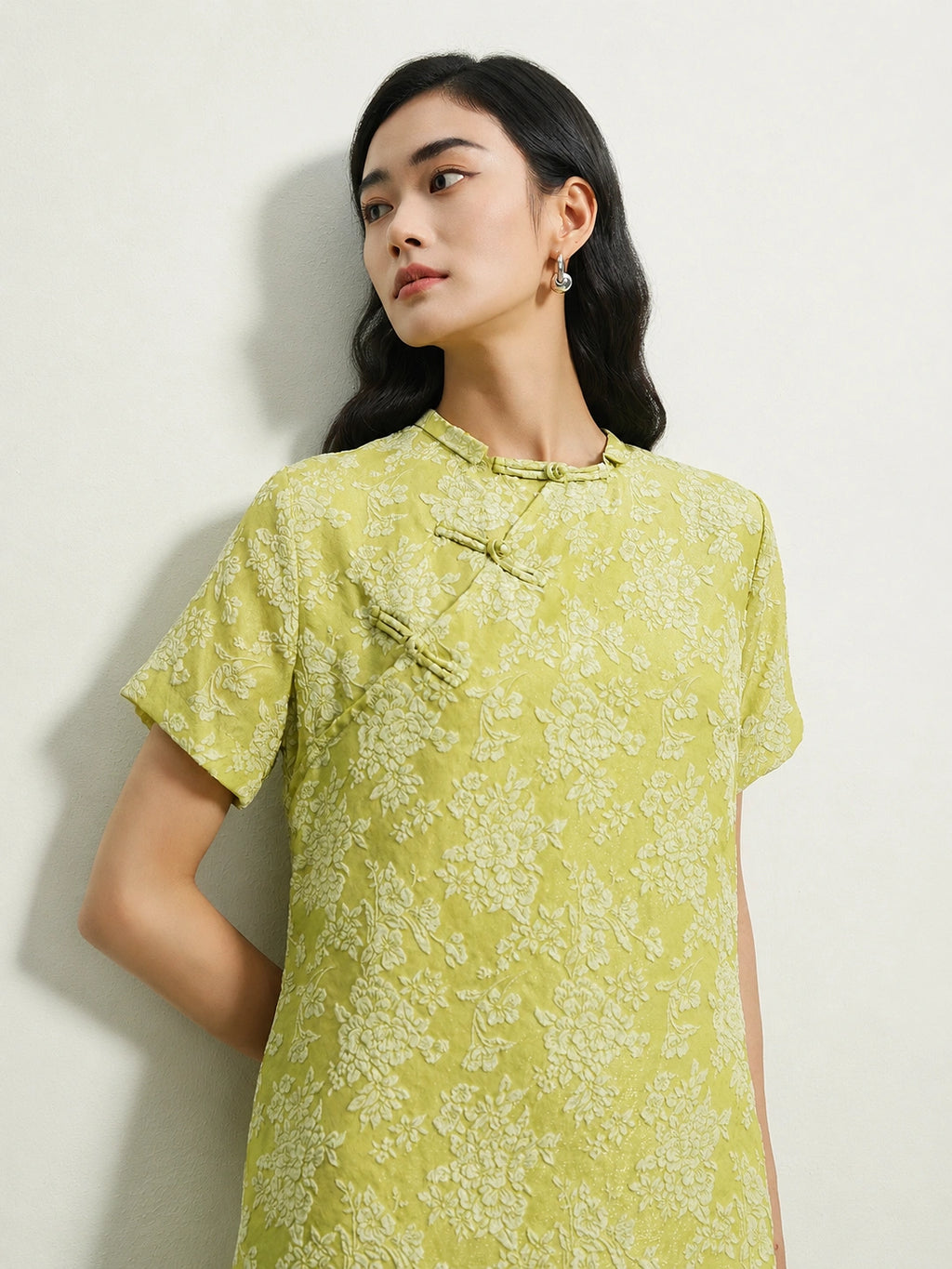 Close-up of handcrafted frog buttons on a light green mulberry silk floral dress.