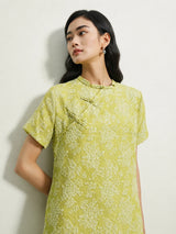 Close-up of handcrafted frog buttons on a light green mulberry silk floral dress.
