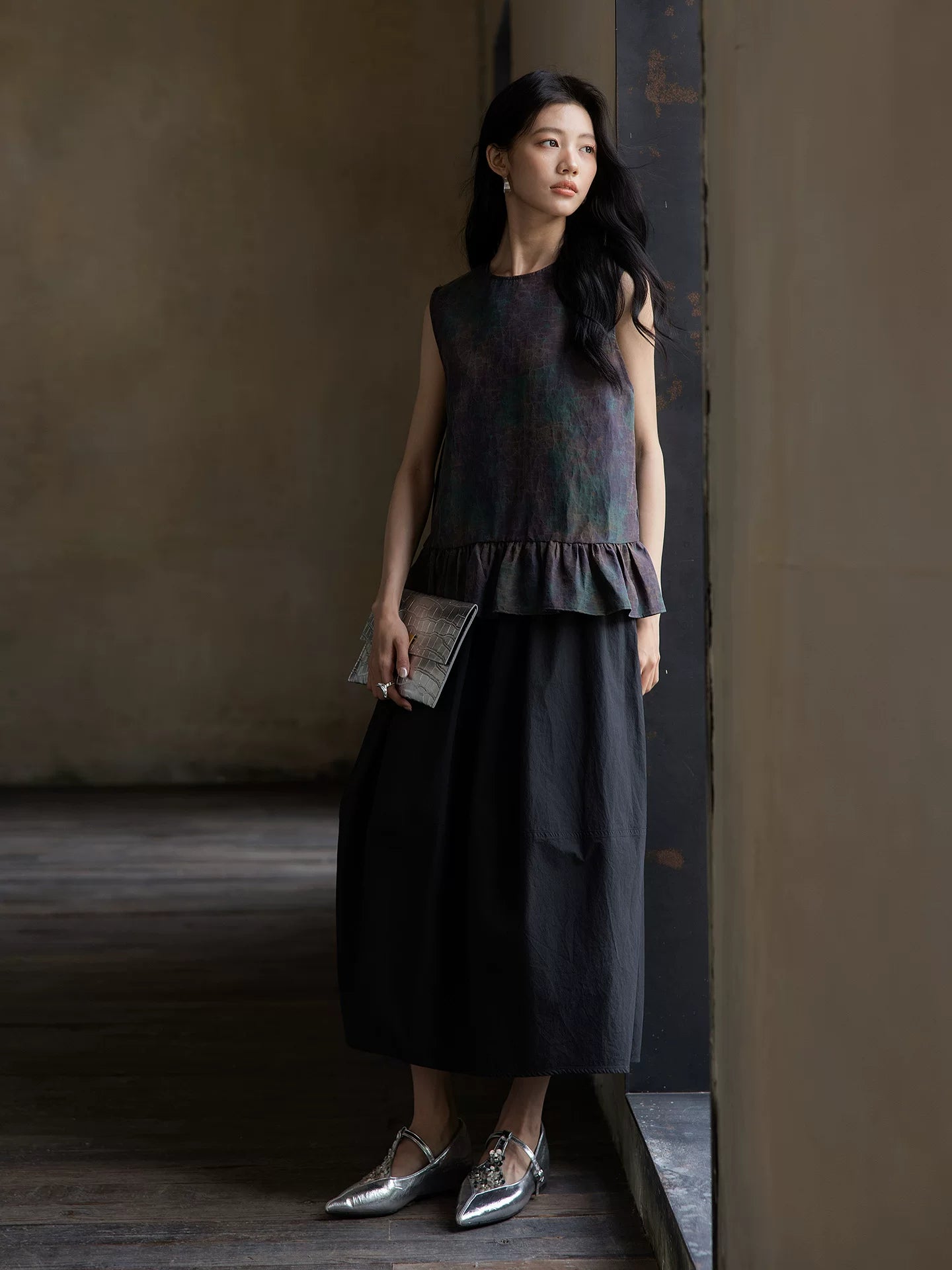 Full-length styling of a 100% mulberry silk sleeveless peplum blouse with a minimalist silhouette.