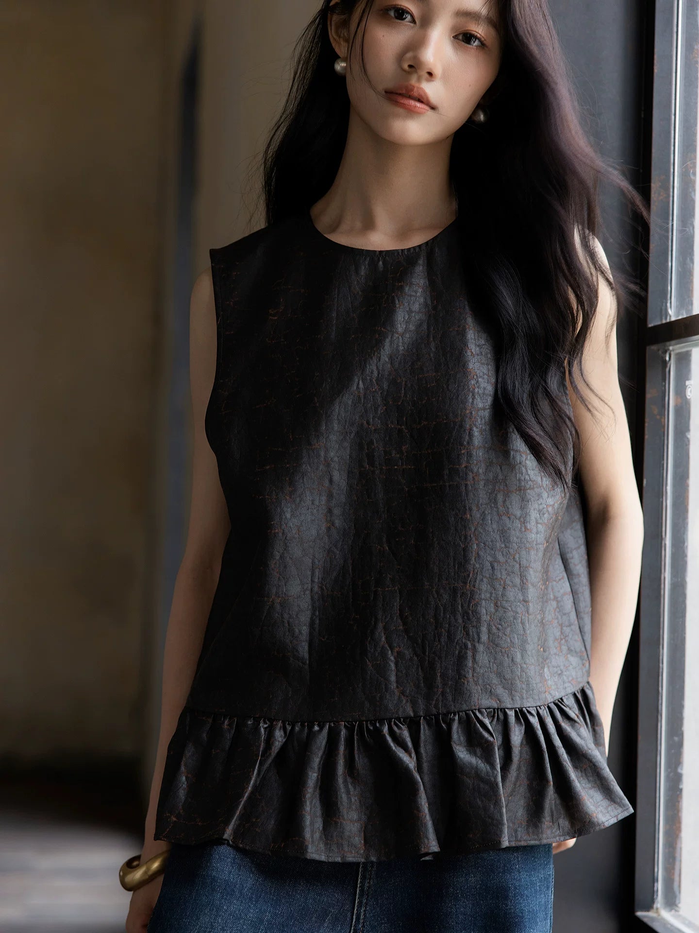 Close-up of a sleeveless Gambiered Silk blouse showing the natural silk texture and peplum hem.