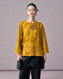 Front view of the mustard gold floral jacquard blouse with asymmetric button fastening