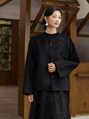 Model wearing the Nanqiao black wool coat with tonal floral embroidery and beaded tassel fastenings.