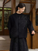 Model looking down while wearing the Nanqiao coat, showing its relaxed shape and wide sleeves.