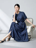 Sitting model in a navy blue silk dress with a tiered skirt and side slits, highlighting the elegant drape and flattering silhouette of the 100% mulberry silk fabric.