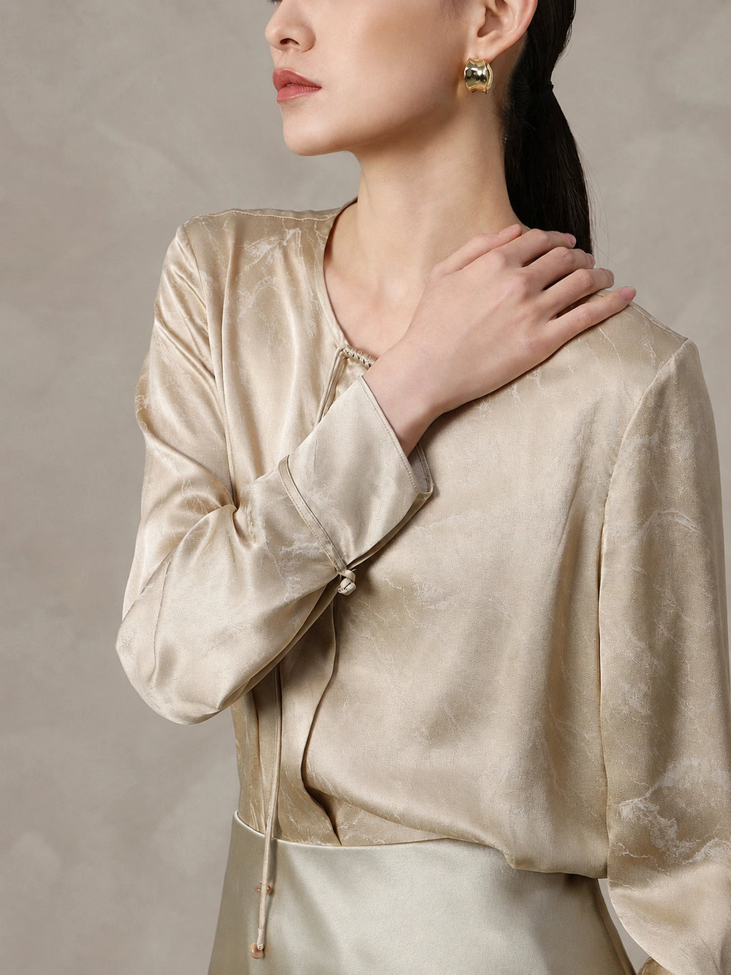 Tie neckline detail on a champagne silk blend blouse