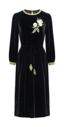 Front view of the black velvet A-line midi dress with floral embellishment and waist tie