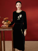 Model wearing the black floral velvet dress beside an autumn flower arrangement