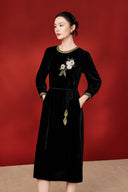 Three-quarter view of the black velvet dress with floral detail and tied waist