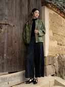 Full-length outfit featuring an olive floral jacket, a black top, dark wide-leg patterned trousers and black shoes.