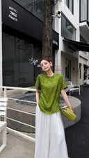 Model wearing a green mandarin collar shirt with traditional frog buttons, paired with a matching green handbag and white pants.