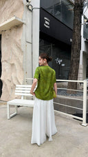 Back view of an olive green Cheongsam top with short sleeves, featuring a subtle jacquard texture, paired with white wide-leg pants.
